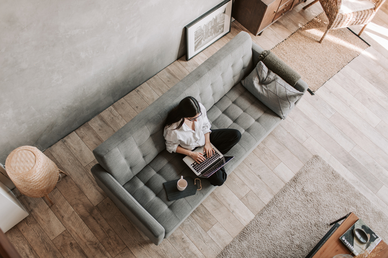 Woman working on a Laptop while seated on a Sofa